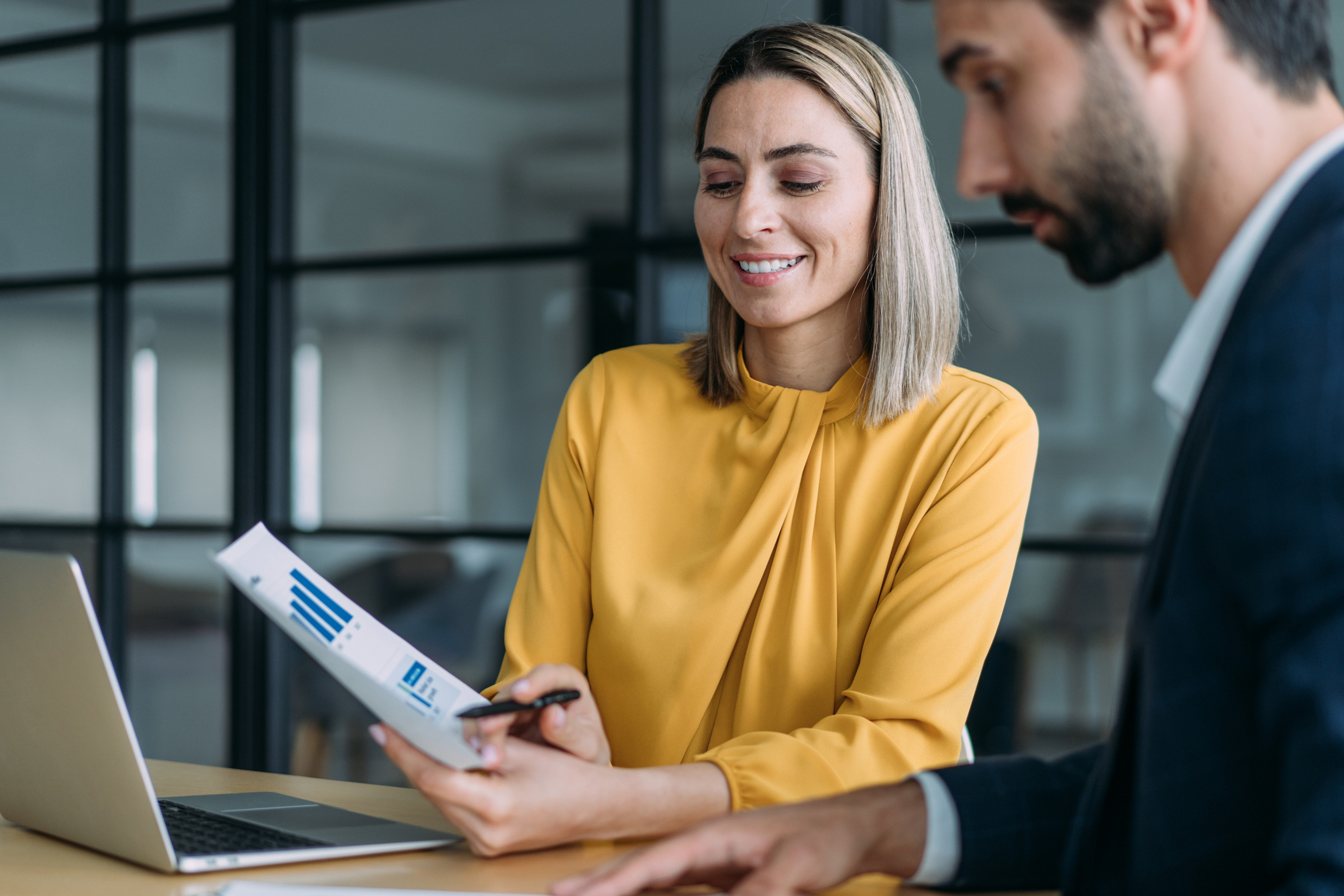 A woman and a man analyzing graphs on a paper.